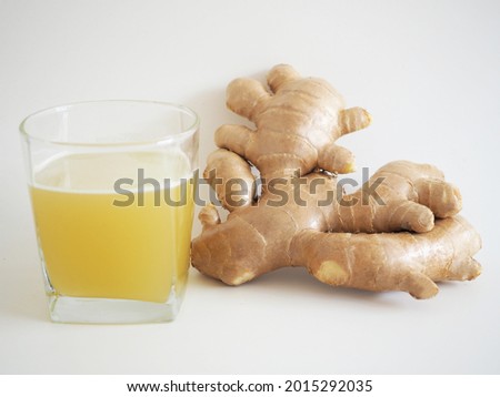 Herbal drink in glass with ginger root on white background. closeup photo, blurred.