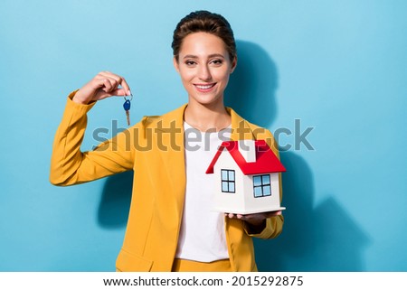 Photo portrait woman in yellow suit smiling keeping key from new house isolated pastel blue color background