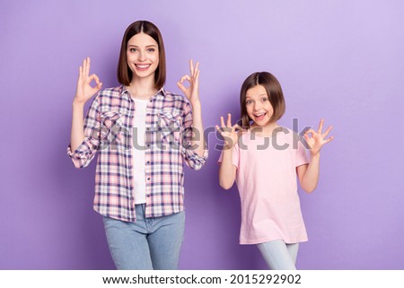 Portrait of two attractive cheerful girls showing ok-sign ad advert isolated over purple violet color background