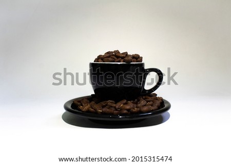 Black cup and coffee beans on white background