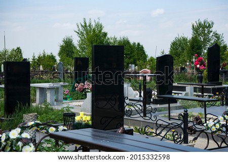City cemetery with black marble monuments above the graves. Recent burials of people in the cemetery. Monolithic monuments over the graves. Royalty-Free Stock Photo #2015332598