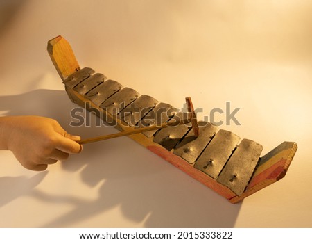 Gamelan toy which is one of the traditional Javanese toys played by a boy's hand on a white background.