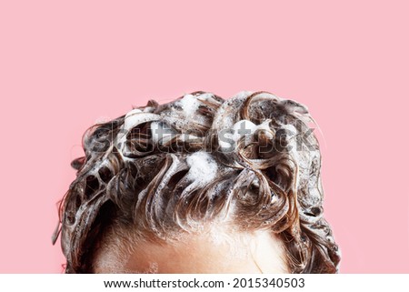 Fmale hair shampoo and foam on pink background close-up. Royalty-Free Stock Photo #2015340503