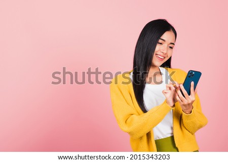 Happy Asian portrait beautiful cute young woman teen smiling excited typing text message on smart mobile phone enjoys online communication isolated, studio shot on pink background with copy space Royalty-Free Stock Photo #2015343203