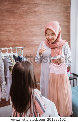 muslim mother shopping with her daughter at boutique clothing shop