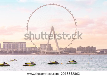Sea scooters and aquabikes as water sports attractions waiting for vacationers against the backdrop of the famous Ferris wheel Dubai Ain Royalty-Free Stock Photo #2015352863