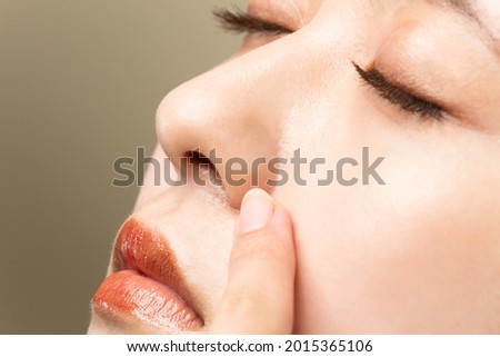 A woman with beautiful skin is pointing at her nose. Royalty-Free Stock Photo #2015365106