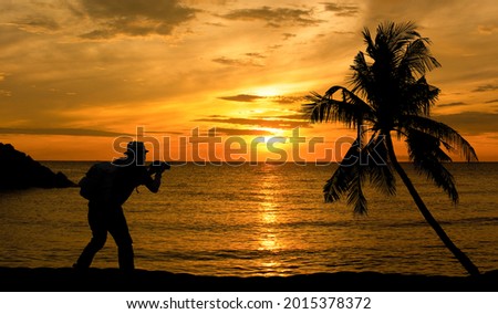 Silhouette of a photographer taking a picture view of the sea at sunset.