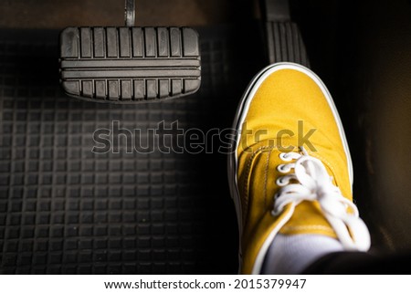 A man in yellow sneakers is stepping on the accelerator of a car. Royalty-Free Stock Photo #2015379947