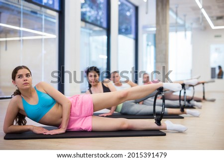 Active people practicing Pilates in the studio on a group class perform exercises with an isotonic circle