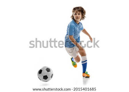 Athletic training. Little sportsman, football soccer player, child playing football isolated on white studio background. Concept of sport, movement, energy and dynamic. Copy space for ad