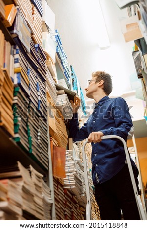 Young intelligent man looking for science materials in the local archive, prepare to write master work. University, academic work, bookworm. Royalty-Free Stock Photo #2015418848