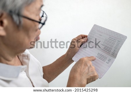 Hands of senior woman holding saving account passbook,checking the sum of money kept and check the amount of elderly pension and subsistence allowance deposits in a bank account,finance in retirement Royalty-Free Stock Photo #2015425298
