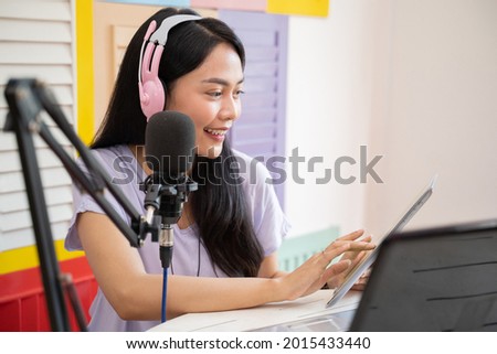 cheerful girl using a tablet and wearing headphones with microphone equipment