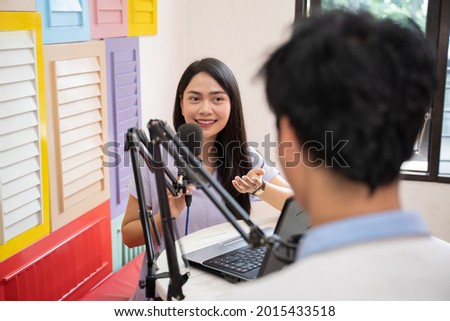 a girl talking and chatting with a guy in front of a microphone during podcast