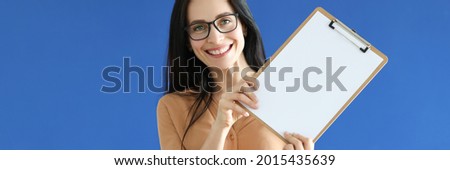 Woman with glasses holding blank sheet of paper in her hands