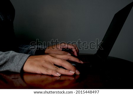 A low exposure picture of hand with mouse and keyboard for hacking and cyber security concept.