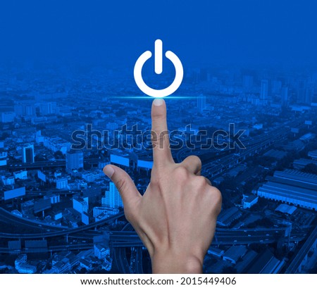 Hand pressing power button over modern office city tower, street and expressway, Start up business concept