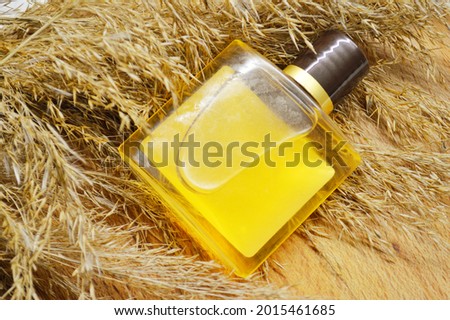 bottle with orange gel lies on fluffy dry grass on a wooden background
