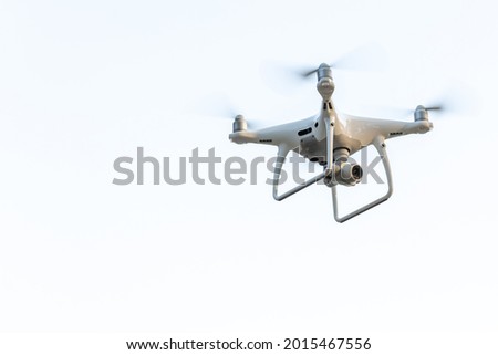 An unmanned aerial vehicle with rotating propellers on a light background. Space for the text.