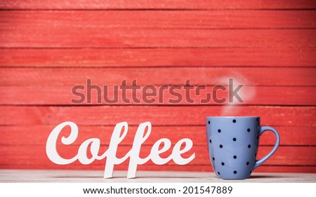 Abstract wooden word Coffee with cup on red wooden background.