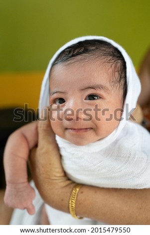 Portrait of cute expression asian new born baby after bath and wrapped with white cloth.Selective focus on baby.