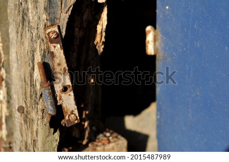 Weathered door frame boards and rusty hinges