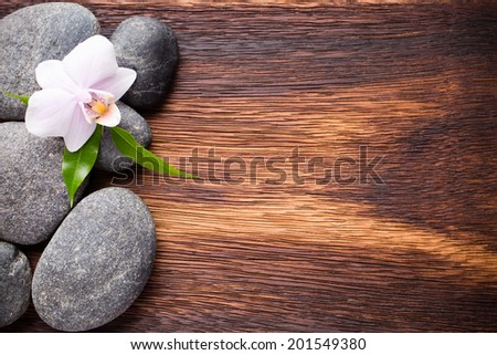 Orchid flower on wooden background with spa stones.