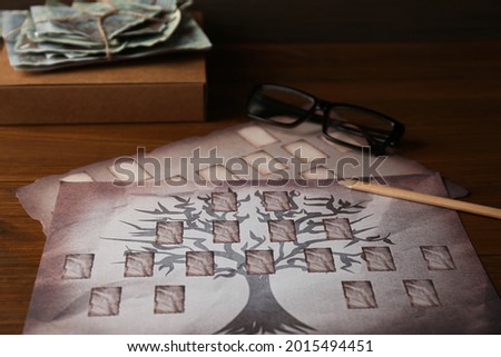 Papers with family tree templates, pencil, photos and glasses on wooden table, closeup