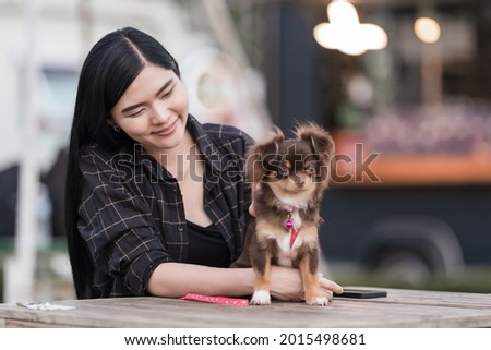 Portrait of a beautiful girl playing with her lovely puppy at outdoor in the public park. Little dog with owner spend a day at the park playing and having fun. Pet love stock photo