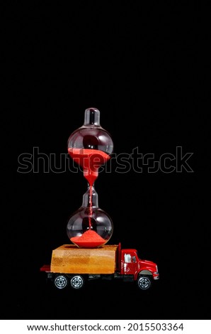 Time Transportation Concept Hourglass Watch on a Red Toy Truck over Black Background