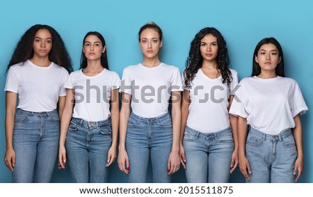 Group Shot Of Five Serious Multicultural Women Posing Looking At Camera Standing Together Over Blue Background In Studio. Females Unity And Diversity Concept. Panorama
