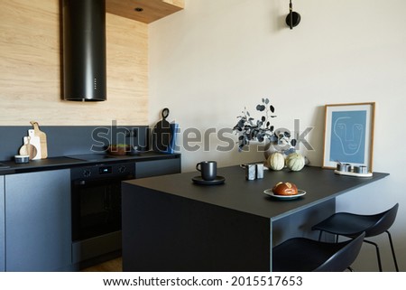 Stylish composition of modern small kitchen interior. Black furniture, workspace and dining space with black and light wooden kitchen accessories. Wooden panel creative walls. Template.