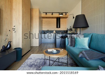 Creative composition of modern living room open space interior in small apartment. Eucalyptus sofa, pillows, small designed wooden coffee table and personal accessories. Carpet on the floor.  Template Royalty-Free Stock Photo #2015518169