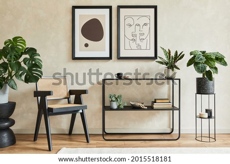 Creative composition of stylish modern living room interior with two mock up poster frames, black geometric commode, armchair, leaf in vase and personal accessories. Neutral colors. Template.
