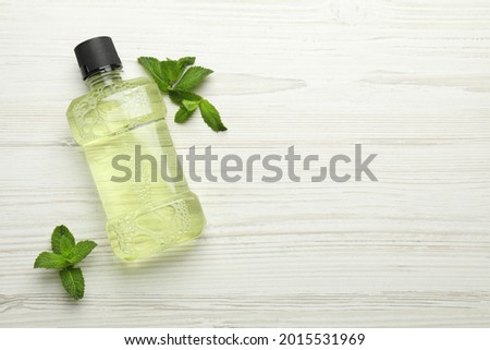 Mouthwash and mint on white wooden background, flat lay. Space for text