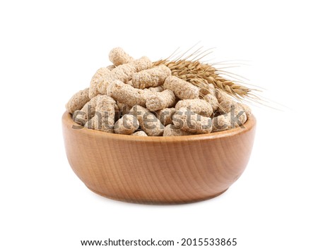 Granulated wheat bran and spikelets in bowl on white background