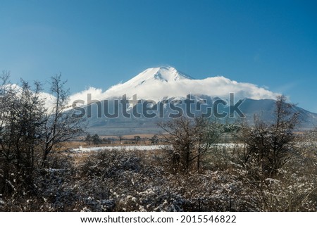 Snow covered Fuji Mountain partially obscured by clouds, during winter in Japan. 