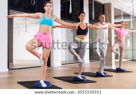 Group of people balancing on pilates balls during group training