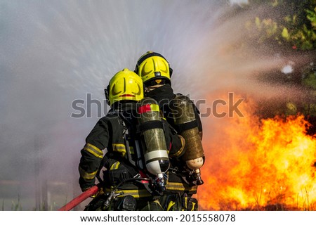 firefighters wearing fire fighter suit for safety and using twirl water extinguisher for fighting the fire flame in emergency situation.. - Safety Firefighter and industrial concept.