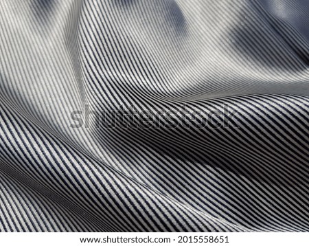 Silk fabric with black and white thin striped print, in folds (texture). 
