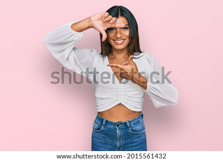 Young latin transsexual transgender woman wearing casual clothes smiling making frame with hands and fingers with happy face. creativity and photography concept. 