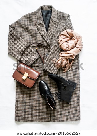 Women's autumn spring clothing ыуе - oversized plaid coat, leather black boots, leather bag, beige cashmere scarf on a light background, top view. Fashion concept