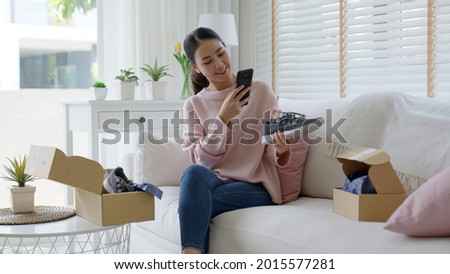 Young asia people happy teen girl smile unbox open gift new shoe buy order from online store shop take photo shoot camera show post social media app blog vlog share sit relax at home sofa couch.