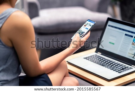 Social media profile page in smartphone screen at work. Woman looking at feed, status update or post with mobile phone. Inefficient lazy worker avoiding job. Follow, like or send friend request.