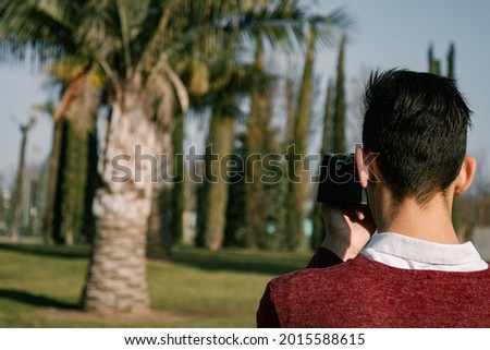 Young guy tourist photographs palm trees. Rest and travel to warm countries.