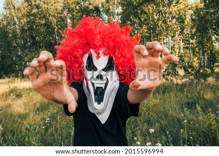 Scary clown kid  on Halloween looks at the camera and takes pictures. Traditions, holidays concept