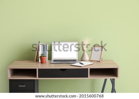 Comfortable workplace with modern laptop near color wall
