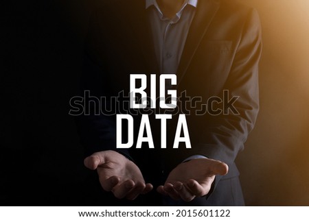 Businessman in a suit on a dark background holds the inscription BIG DATA. Storage Network Online Server Concept.Social network or business analytics representation.