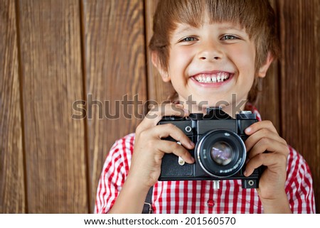 Cheerful smiling child (boy) holding a camera